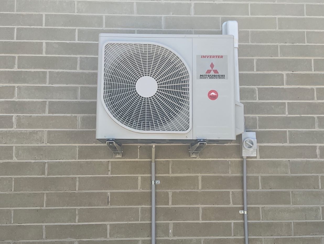 Outdoor air conditioning unit mounted on a brick wall